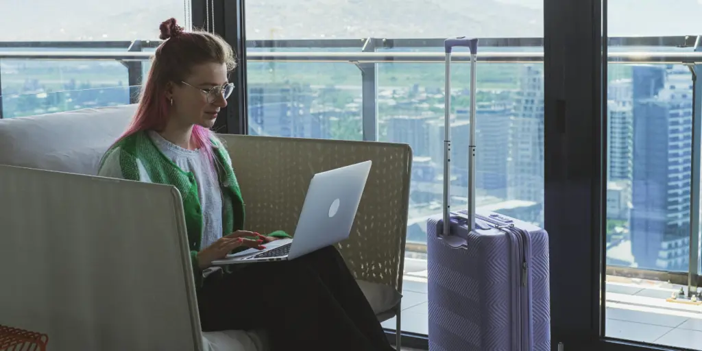 Professionista in viaggio lavora al laptop con valigia in Coworking a Milano